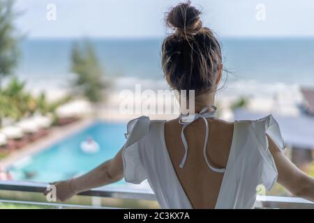 Gril thaïlandais le whirt robe ling code vestimentaire est debout en face de la chambre à coucher avec terrasse et piscine simming phanoramic sur la mer en face d'elle. Banque D'Images