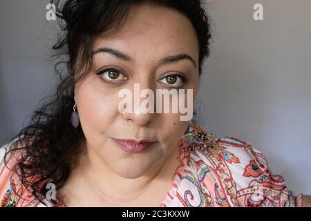 Portrait d'une belle femme hispanique avec de longs cheveux fclés foncés et une chemise fleurie Banque D'Images