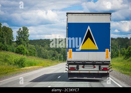 Un camion avec le drapeau national de Sainte-Lucie représenté sur la porte arrière transporte des marchandises vers un autre pays le long de la route. Concept d'exportation-importation Banque D'Images