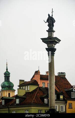 Photo verticale de la colonne de Sigismund sur fond de bâtiments colorés Banque D'Images