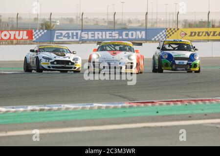 DUBAÏ - JANVIER 14 : Aston Martin Vantage, Porsche 997 et BMW mini se battent pour prendre des positions lors de la course Dunlop 24 heures 2012 à l'aérodrome de Dubaï sur Ja Banque D'Images