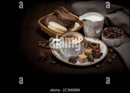 La vie de collection avec une tasse de café, des macarons, des grains de café, de la crème et des serviettes en lin sont sur fond sombre, avec un espace de copie Banque D'Images