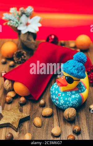 Photo d'une chaussette décorative rouge pleine de noix et mandarines et canard en caoutchouc à côté Banque D'Images