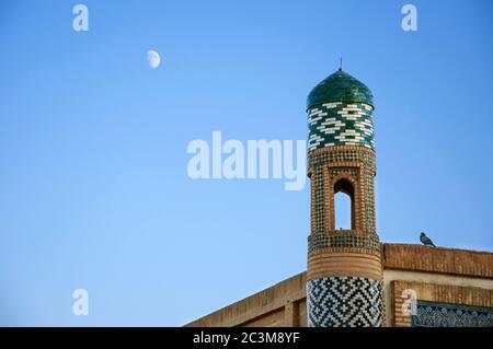 Tour islamique avec le pigeon assis sur le mur sur le ciel bleu et le fond de lune dans la ville antique Khiva en Ouzbékistan Banque D'Images