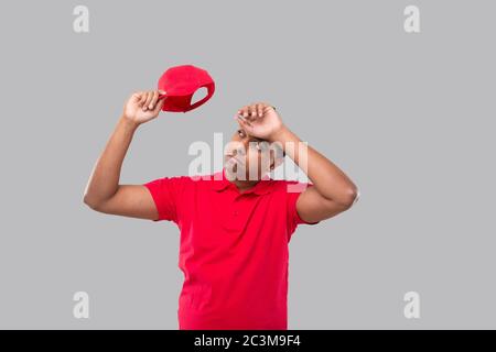 L'homme de livraison est fatigué après le travail. Affiche de livraison indienne pour garçon fatigué. Uniforme rouge Banque D'Images