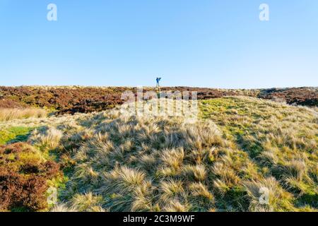 Un matin d'hiver lumineux sous Stanage Edge, la figure d'un photogrpaher se dresse sur la ligne d'horizon éloignée Banque D'Images