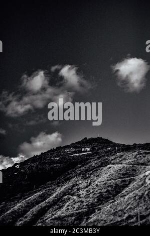 Prise de vue verticale en niveaux de gris d'une belle colline sous les nuages dans le ciel capturé à partir d'un angle bas Banque D'Images
