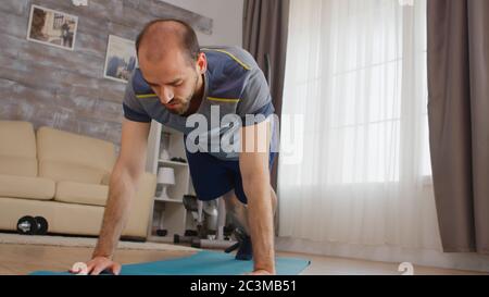 Homme sportif faisant alpinistes s'entraîner sur tapis de yoga à la maison portant des vêtements de sport. Banque D'Images