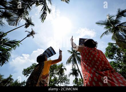 Kolkata, Inde. 21 juin 2020. Deux femmes ont vu observer l'éclipse solaire depuis une terrasse en utilisant une plaque à rayons X. l'éclipse solaire partielle à Kolkata durera environ trois heures et 31 minutes. Il a commencé à 10:46 heure locale et se terminera à 2:17 heures pendant cette période, environ 67% du Soleil sera couvert par l'ombre de la Lune . Crédit : SOPA Images Limited/Alamy Live News Banque D'Images