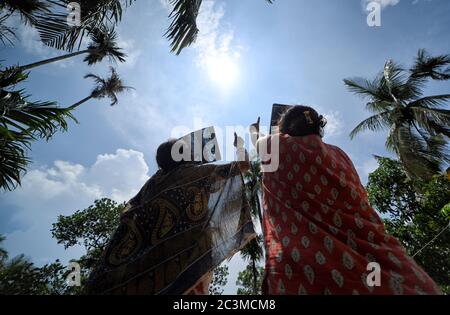 Kolkata, Inde. 21 juin 2020. Les femmes ont vu observer l'éclipse solaire depuis une terrasse à l'aide d'une plaque à rayons X. l'éclipse solaire partielle à Kolkata durera environ trois heures et 31 minutes. Il a commencé à 10:46 heure locale et se terminera à 2:17 heures pendant cette période, environ 67% du Soleil sera couvert par l'ombre de la Lune. Crédit : SOPA Images Limited/Alamy Live News Banque D'Images