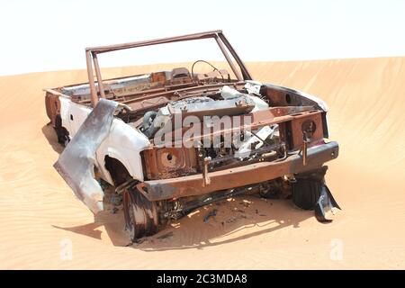 L'épave de véhicules en 4x4 (quatre roues motrices) rouillés et partiellement enfoui dans les dunes de sable du désert arabe. Le sable est lentement en train d'engloutir l'épave. Banque D'Images