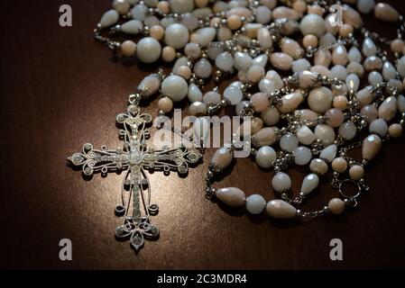 Gros plan d'un beau collier blanc avec perles et une croix blanche recouverte de cristaux Banque D'Images