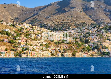 Soleil en fin d'après-midi sur les demeures néo-classiques du port de Gialos et de l'ancienne colline de Horio, l'île de Symi, Dodécanèse, Grèce Banque D'Images