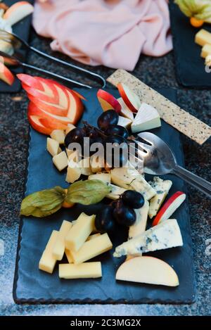 Gros plan grand angle de fromage et de fruits sur un bureau noir Banque D'Images
