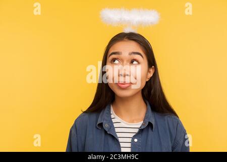 Je suis ange! Portrait d'une fille réfléchie regardant nimbus au-dessus de sa tête, fantasisant sur le paradis, la vie du ciel, la question de réfléchir avec le visage pensif. Banque D'Images