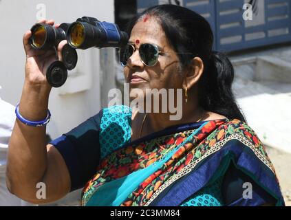 Beawar, Rajasthan, Inde, 21 juin 2020 : une femme indienne regarde l'éclipse solaire annuelle à travers des jumelles, à Beawar. Crédit : Sumit Saraswat/Alay Live News Banque D'Images