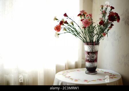 Bouquet de fleurs d'asters sur une table avec une nappe en lin dans une chambre près de la fenêtre Banque D'Images