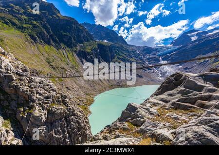 Vue imprenable sur le pont suspendu, le pont de Trift au-dessus du lac de Trift (Triftsee) et le glacier, canton de Berne, Suisse. Banque D'Images