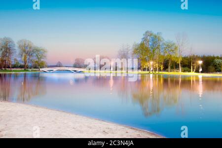 Belle photo d'un lac avec réflexion des lumières du parc il et un pont blanc Banque D'Images
