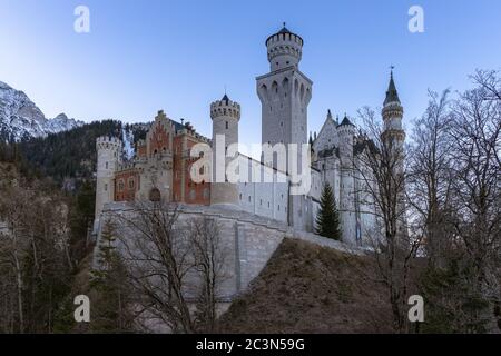 Vue extérieure du célèbre château de Neuschwanstein en hiver le matin, avec ciel bleu et neige montagnes couvertes en arrière-plan, Fussen (Fuessen), B Banque D'Images