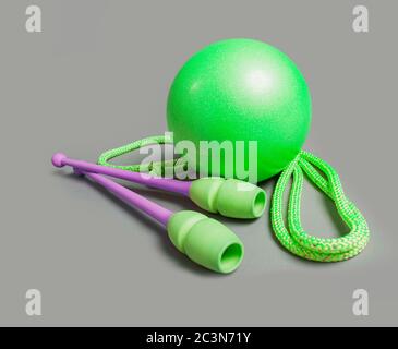 Équipement professionnel pour l'entraînement de gymnastique sur fond gris. Balle verte, mace et corde pour la gymnastique. Banque D'Images