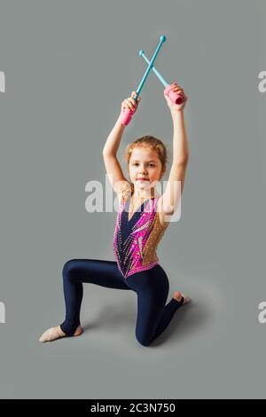 Bonne fillette de gymnastique dans un costume, tenant des bâtons Banque D'Images