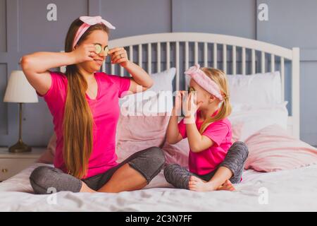 Jeune femme et petite fille tenant des tranches de concombre comme des lunettes Banque D'Images