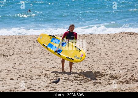Bournemouth, Dorset, Royaume-Uni. 21 juin 2020. RNLI Lifesest de retour sur certaines plages de Bournemouth, alors que les températures s'élèveront en semaine pour une mini-vague de chaleur qui attirera la foule sur les plages. Femme RNLI Lifeguard tenant un surf de la vie de traîneau sur la plage. Crédit : Carolyn Jenkins/Alay Live News Banque D'Images