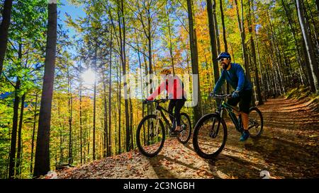 Femme et homme à vélo, à vélo, au coucher du soleil, dans les montagnes, paysage forestier. Couple de vélo de piste de débit MTB endoro. Activités sportives en plein air. Banque D'Images