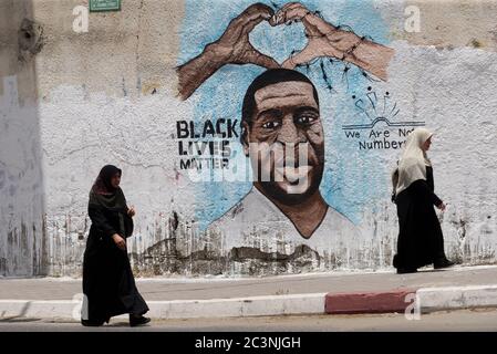 Gaza, Gaza. 21 juin 2020. Des femmes palestiniennes marchent devant une fresque représentant George Floyd, un homme afro-américain sans armes qui est décédé pendant sa détention à Minneapolis, à Gaza, le dimanche 21 juin 2020. Photo par Ismael Mohamad/UPI crédit: UPI/Alay Live News Banque D'Images