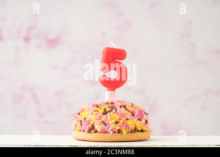 un petit gâteau coloré avec la bougie en forme de cinq pour la fête d'anniversaire Banque D'Images