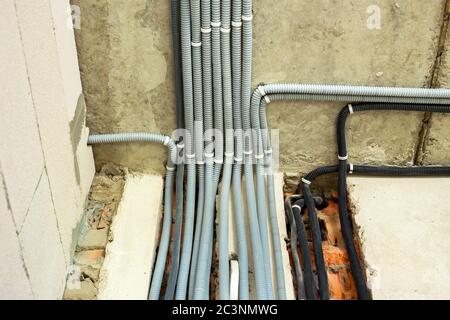 Câbles électriques posés dans une ondulation de protection installée au plafond et au mur dans une pièce en cours de construction. Banque D'Images