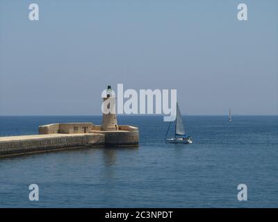 VALLETTA, MALTE - 14 juillet 2013 : le brise-lames qui protège l'entrée du Grand Port des vagues de la Valette, Malte. Phare à la Banque D'Images