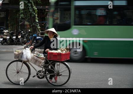 Une vieille femme vietnamienne s'arrête et vend de la nourriture de rue dans la rue animée. Ho Chi Minh ville, Vietnam, 17 mars 2017. Banque D'Images