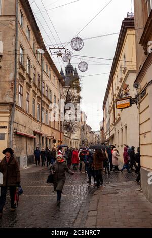 Lviv, Ukraine - 4 janvier 2020 : rue de la vieille ville avec des personnes marchant sur des pavés le jour pluvieux d'hiver, temps nuageux Banque D'Images