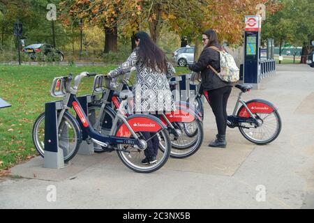 Deux femmes à vélo rack avec Santander de location de vélos à Hyde Park, Londres, Royaume-Uni Banque D'Images
