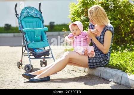 jeune mère marchant avec un bébé assis dans une poussette. mère et petite fille. Banque D'Images