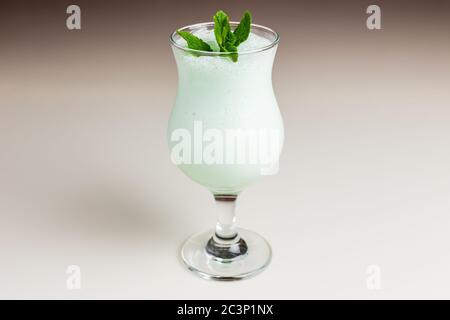 Un milkshake vert vif dans un verre d'ouragan garni d'une branche de menthe Banque D'Images