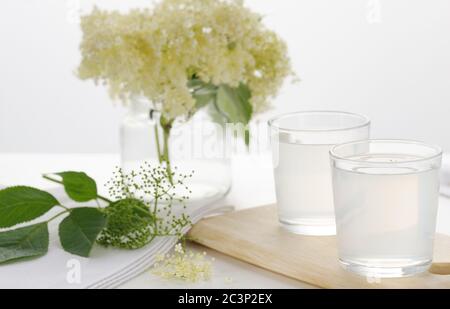 Limonade de sureau rafraîchissante maison et grappe de fleurs de sureau sur fond blanc.image avec foyer sélectif, horizontal. Banque D'Images