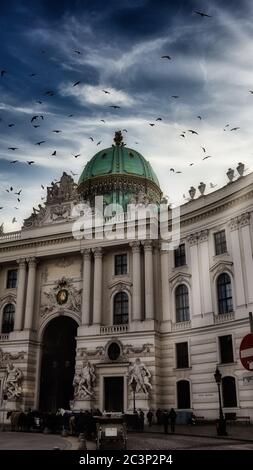 Troupeau d'oiseaux volant dans le ciel sombre au-dessus de Hofburg, Vienne, Autriche Banque D'Images