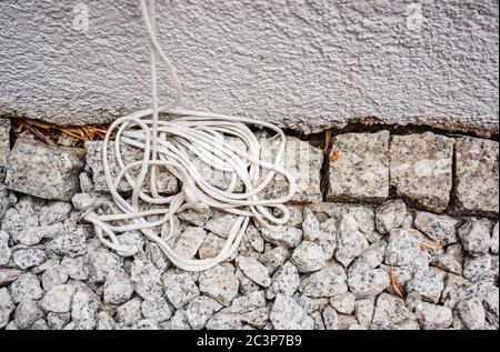 Plan vertical de fils blancs sur des pierres blanches contre un mur peint en blanc Banque D'Images