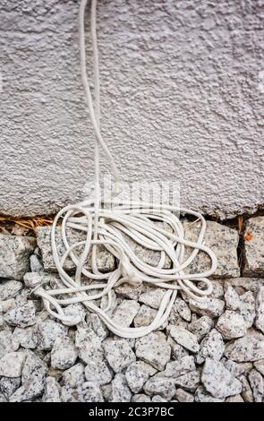 Plan vertical de fils blancs sur des pierres blanches contre un mur peint en blanc Banque D'Images