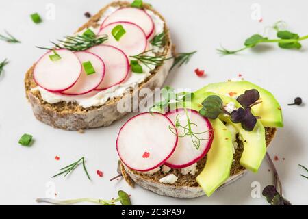 Des rôtis de printemps et d'avocat sains avec fromage cottage, pousses et poivre sur une table en marbre blanc pour un petit déjeuner sain. Gros plan Banque D'Images