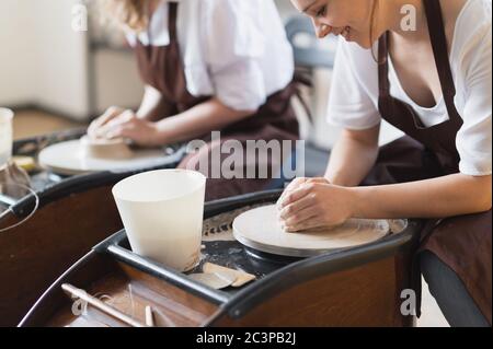 Deux artistes de céramique femelle en tablier utilisant du matériel d'argile travaillant dans le studio de potter. Formation à distance en soirée. Aventure de loisirs pour adultes. Hiver Banque D'Images