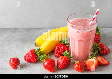 Verre de smoothie sain ou milkshake fait de lait de fraise, de banane et d'amande avec une paille. Concept de boisson crue, végétalienne et végétarienne Banque D'Images