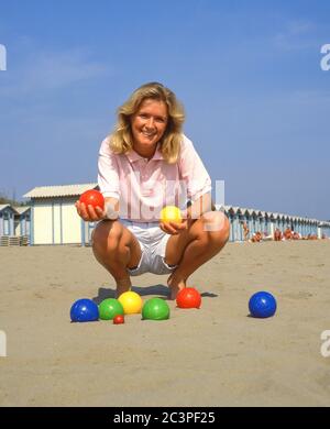 Jeune femme jouant au jeu de boules sur la plage, Lido di Jesolo, province de Venise, région de Vénétie, Italie Banque D'Images