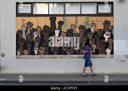 LOS ANGELES, ÉTATS-UNIS. 19 2020 JUIN : une femme passe devant une fresque avec des poings noirs sur le marché immobilier de Mark Kuwata lors d'un rassemblement organisé par No More Names LA pour célébrer le dix-septième au City Hall dans le centre de Los Angeles, le vendredi 19 juin 2020. Junetdix est la fête célébrant le jour de 1865 que les Noirs asservis à Galveston, Texas, ont appris qu'ils avaient été libérés de la servitude, plus de deux ans après la Proclamation d'émancipation. (Photo par IOS/Espa-Images) Banque D'Images