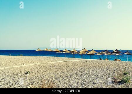 Rangée de parasols en paille sur la plage vide, bleu clair et ciel, plage tropicale paradisiaque, détente. Personne. Banque D'Images