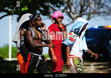 MIAMI - 16 MARS 2019 : des jeunes hommes marchent devant une voiture de police qui clignote sur Ocean Drive à South Beach pendant les vacances de printemps annuelles. Banque D'Images