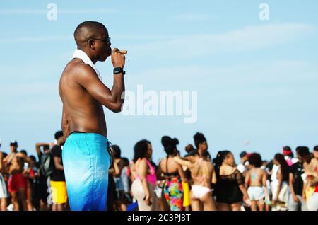 MIAMI - 16 MARS 2019 : un jeune homme fume un cigare lors d'un rassemblement de jeunes étudiants célébrant les vacances de printemps à South Beach. Banque D'Images